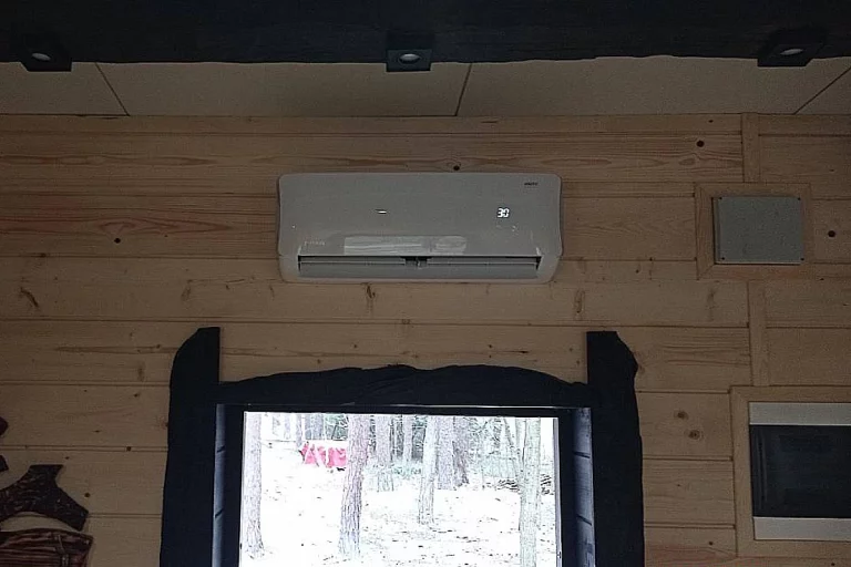Biały klimatyzator do ogrzewania domku letniskowego zamontowany nad drzwiami wejściowymi