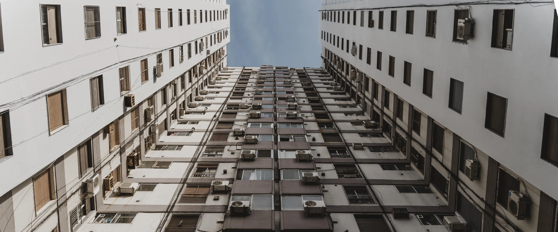 Widok z poziomu zero na blok z zamontowanymi na ścianach klimatyzatorami